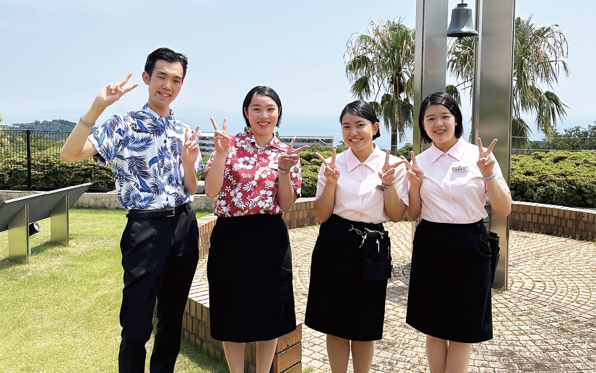 男女四人が青空の下でピースをしている様子